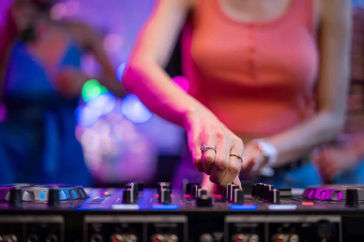 DJ adjusting music mixer at party.