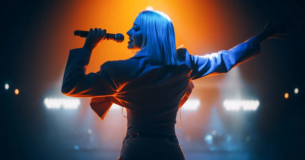 Singer performing on stage with dramatic lighting.