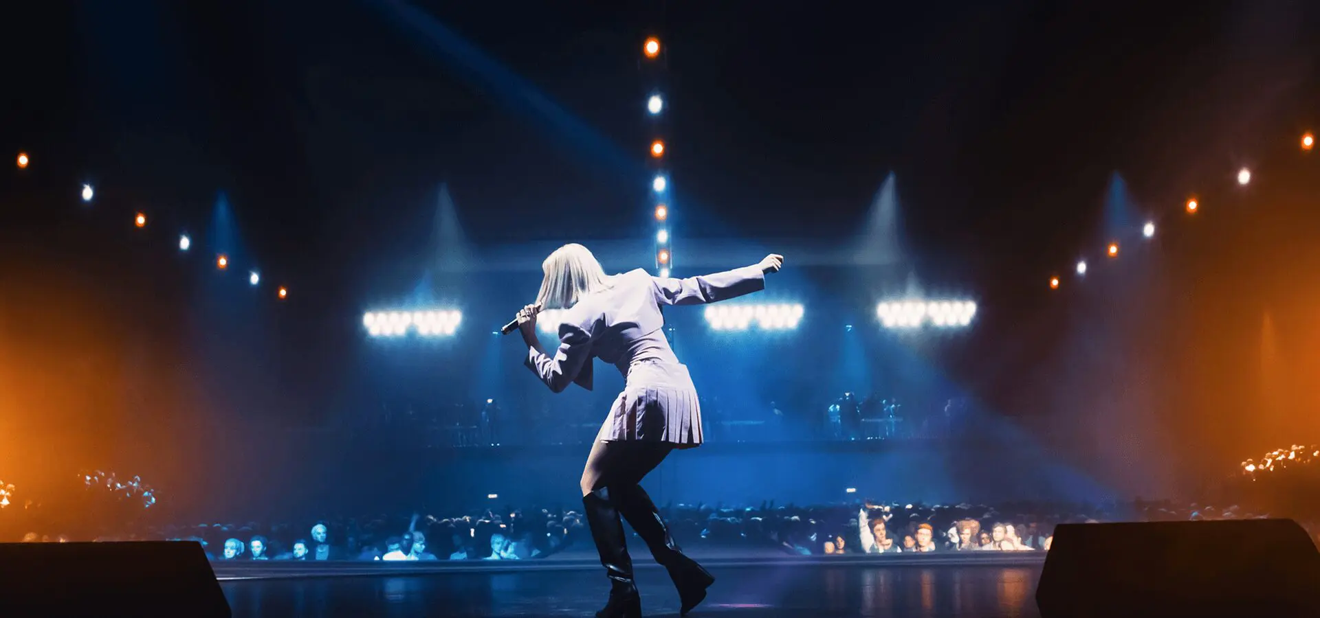 A singer in the spotlight, surrounded by dramatic beams of light.