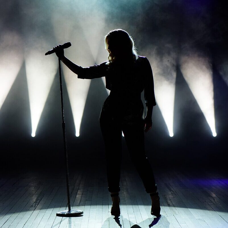 Singer silhouetted on stage with microphone stand.